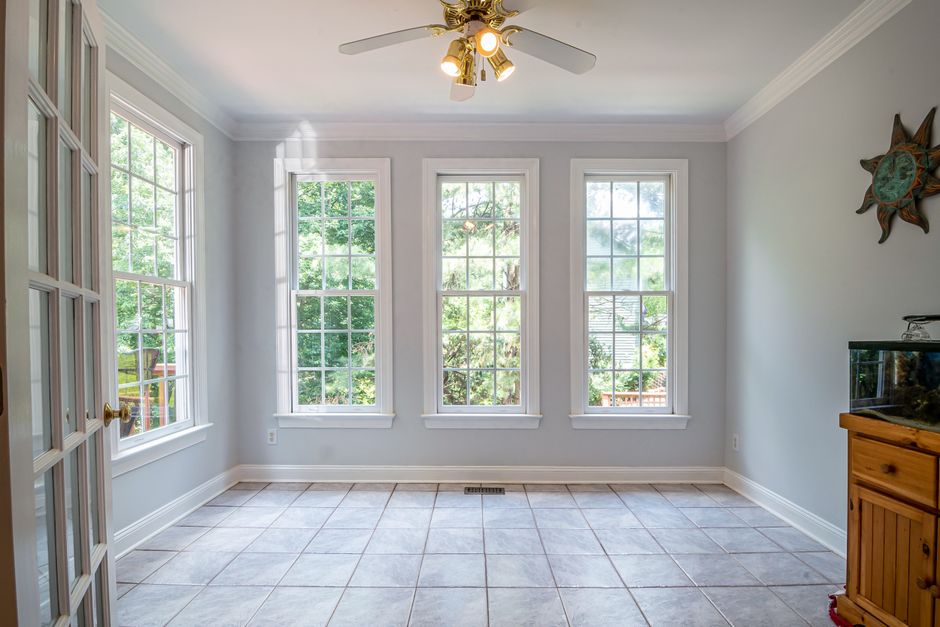 Bright room with three tall double hung windows with white frames and a tile floor