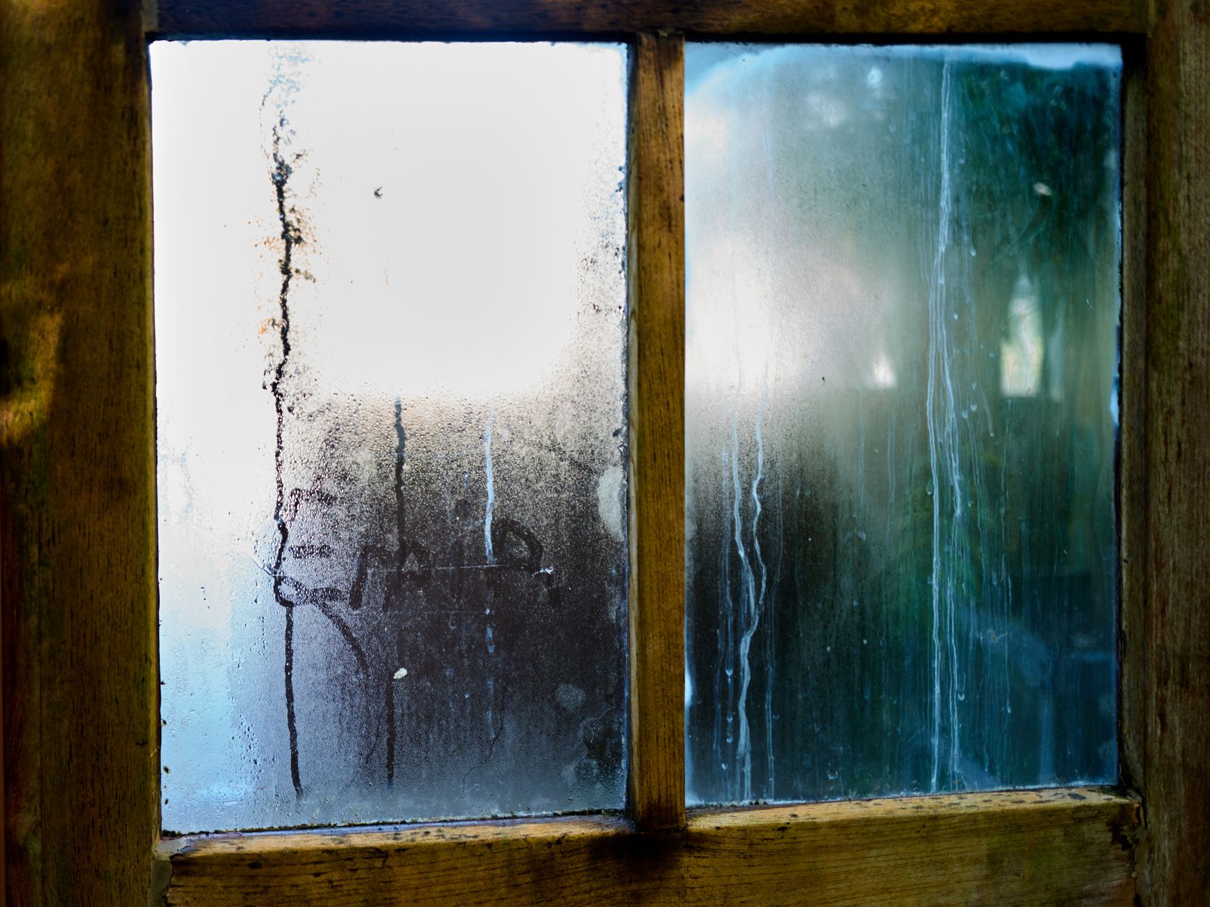 Close view of condensation streaking down a window pane